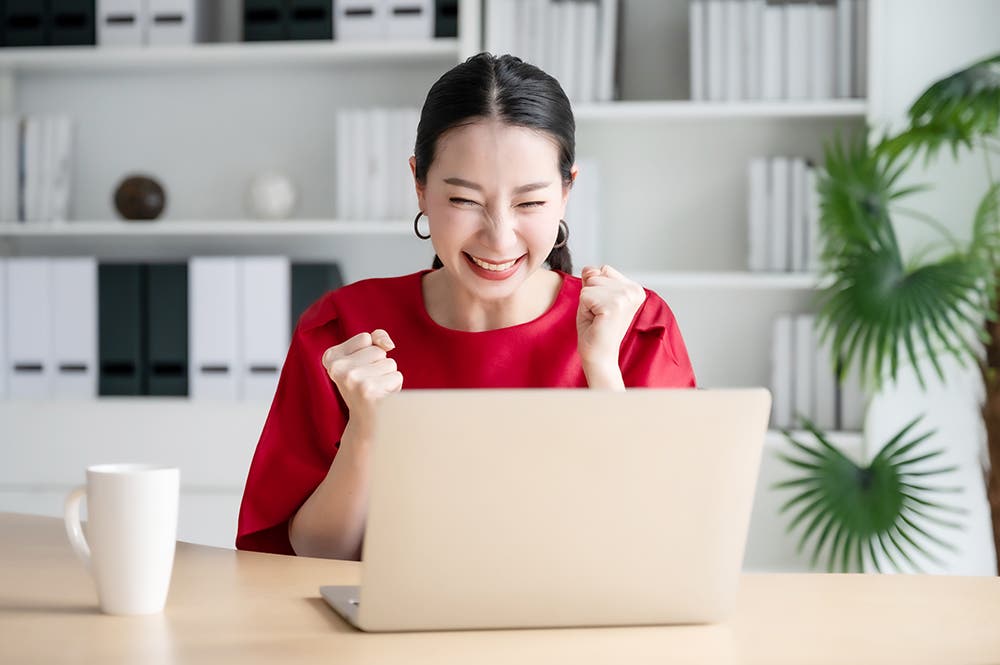 Women is looking on her laptop and is happy